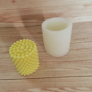 Detail einer zylindrischen Kerzenform mit Noppenstruktur und fertigem Wachsstück