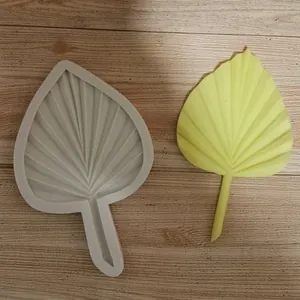 Detailaufnahme einer Silikonform für Palmblätter neben einem fertigen Blatt aus Fondant.