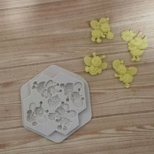 Silikonform Cartoon-Biene mit fertigen gelben Fondant-Figuren auf Holzhintergrund