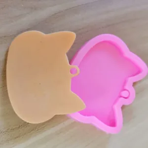 Close-up detail showing the cat-shaped pink silicone mold with a beige resin casting