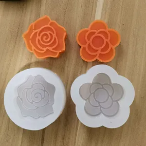 Detailansicht von Rosen- und Kamelien-Silikonformen mit fertigen orangefarbenen Seifen
