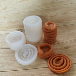 Detailansicht von Schlangen-Silikonformen und fertigen Modellen auf Holzoberfläche.