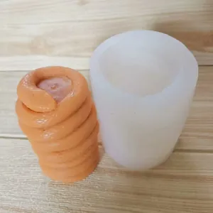 Silikonform für gewundene Schlangen mit fertiger orangefarbener Wachskerze auf Holz