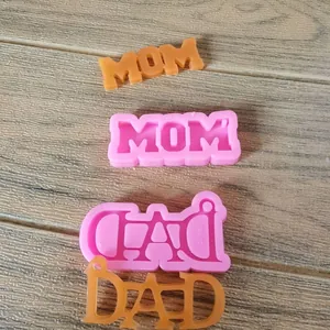 Primer plano de moldes de silicona MOM y DAD con piezas de resina acabadas en madera.