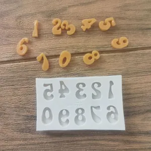 Detail view of a silicone number mold with molded orange digits on a wood background