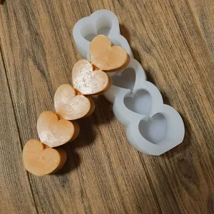 Detailweergave van een siliconen mal met 5 hartjes en oranje wasmonsters op hout.