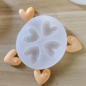 A macro view of a 4-cavity heart silicone mold with finished orange clay hearts.
