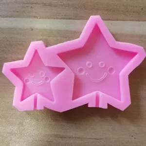 Detail view of a pink silicone baking mold with two star-shaped smiley face cavities.
