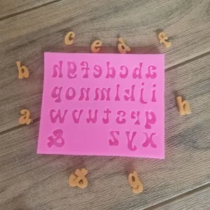 Detailed view of pink silicone alphabet mold with scattered fondant letters