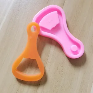 Vue détaillée d'un moule en silicone rose pour ouvre-bouteille et une pièce en résine orange