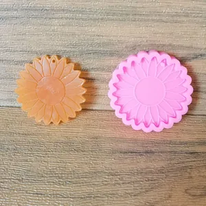 Detalle de un molde de silicona de girasol rosa junto a una pieza de resina terminada