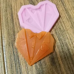 Detailansicht einer herzförmigen Smoking-Anzug-Silikonform mit orangefarbenem Fondant-Guss