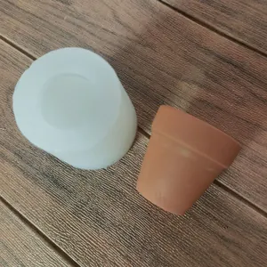 Detail view of white silicone mold and finished clay succulent flower pot on wood