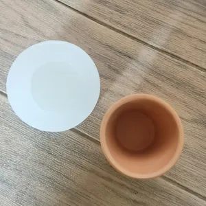 Top view of a round silicone mold alongside a finished terracotta clay flower pot