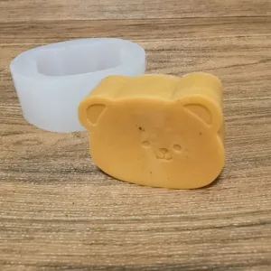 Macro view of cute bear silicone mold and finished aromatherapy candle on wood surface