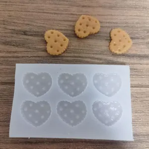 Detalle de un molde de silicona de 6 cavidades con forma de galleta de corazón en madera