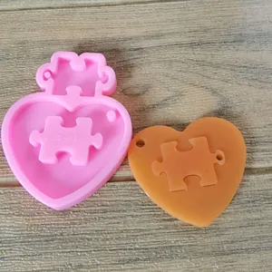 Detailed view of pink heart puzzle silicone mold with finished orange resin keychain piece