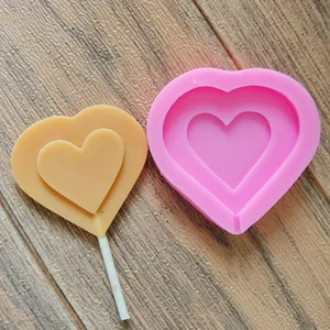 Stampo per lecca-lecca in silicone a forma di cuore con un lecca-lecca beige su legno