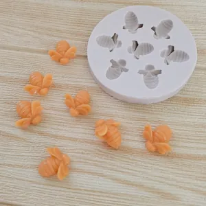Close-up of a 7-cavity bee-shaped silicone mold with finished orange bees on wood