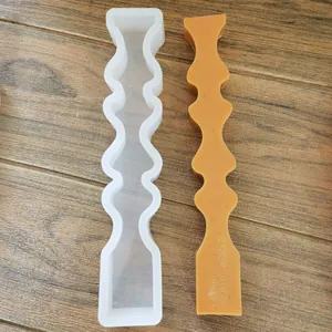 Comparación de un molde de silicona ondulado blanco y una vela aromática amarilla.