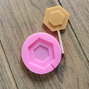 Dettaglio dello stampo per lecca-lecca esagonale in silicone rosa con lecca-lecca su legno