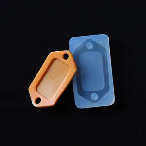 Dettaglio di uno stampo in silicone rettangolare e di una piastrina in resina arancio.