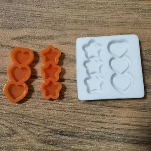 Detailansicht von weißen und orangen herz- und sternförmigen Silikon-Backformen auf Holz.