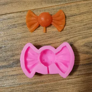 Detailansicht einer rosa Silikonform für Schleifen-Lollipops und einer orangefarbenen Süßigkeit