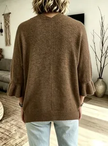 Vista posteriore di un comodo cardigan in maglia marrone oversize con maniche a volant