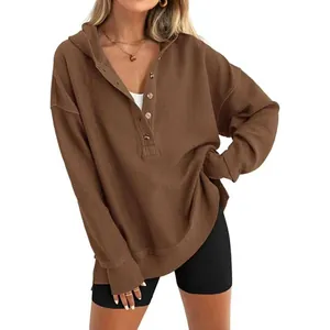 Vue détaillée d'un sweat à capuche marron en maille gaufrée avec boutons Henley et coupe large.