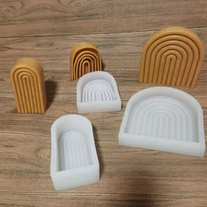 Détail des moules en silicone arc-en-ciel et bougies en cire sur une surface en bois