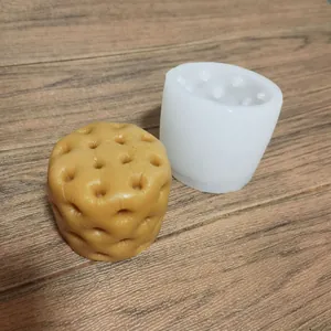 Detailed view of a white cylindrical silicone mold next to a honeycomb textured brown candle
