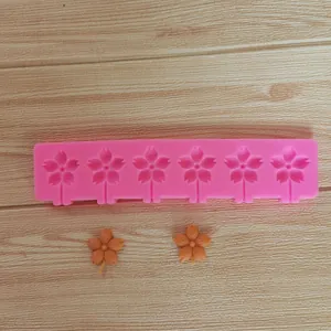 Detail of a pink sakura flower silicone mold showing six cavities and finished pieces