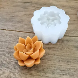 Detailed view of a succulent silicone mold and finished orange-yellow wax flower on wood.