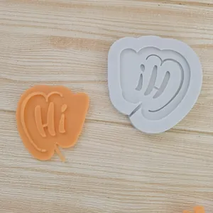 Macro detail of 'Hi' speech bubble silicone mold alongside an orange finished piece