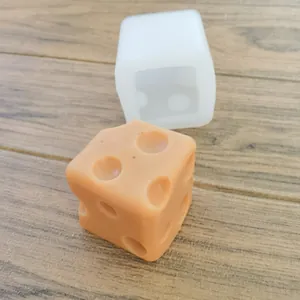 Detail view of square dice silicone mold with a finished aromatic wax dice on wood