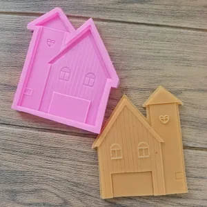 Détail montrant un moule en silicone rose en forme de maison et son biscuit terminé.