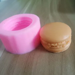 Close-up van een roze macaron siliconen mal met afgewerkte DIY taartdecoratie detail.