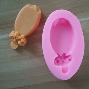 Detail view of a pink silicone ice cream popsicle mold and a finished fondant sample.