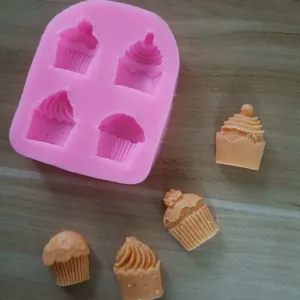 Detail view of pink silicone mold with finished cupcake-shaped fondant decorations on wood