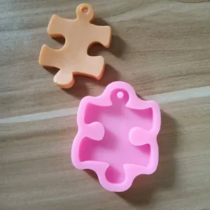 Close-up view of pink puzzle shaped silicone mold with an orange cast sample on wood