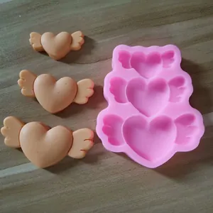Detailed macro view of pink silicone mold with heart wing shapes and molded items