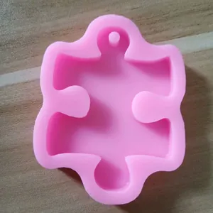 Detailed view of pink jigsaw puzzle shaped silicone mold for DIY keychain and craft making.