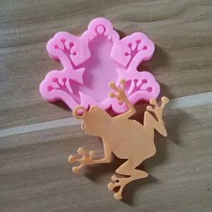 Detail shot of a pink frog-shaped silicone mold and a finished resin frog figurine.