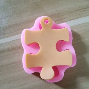 Detail view of a pink silicone puzzle piece mold for DIY crafts on a wooden surface.