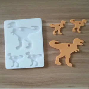 Kreative Silikonform in Dinosaurierform mit fertigen orangefarbenen Anhängern auf Holzhintergrund