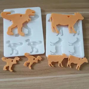 Nahaufnahme von Silikonformen in Dino- und Kuhform mit orangefarbenen Harzproben