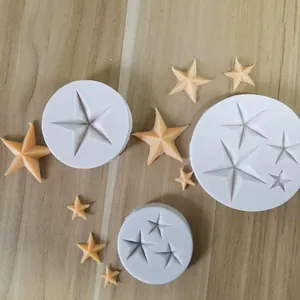 Vista superior de tres moldes de estrellas de silicona blanca con estrellas