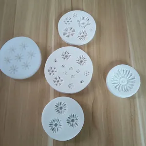 Close-up of five white silicone molds with various chrysanthemum flower patterns.