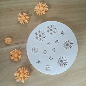 Detail showing white silicone mold with various daisy flower cavities for fondant cake